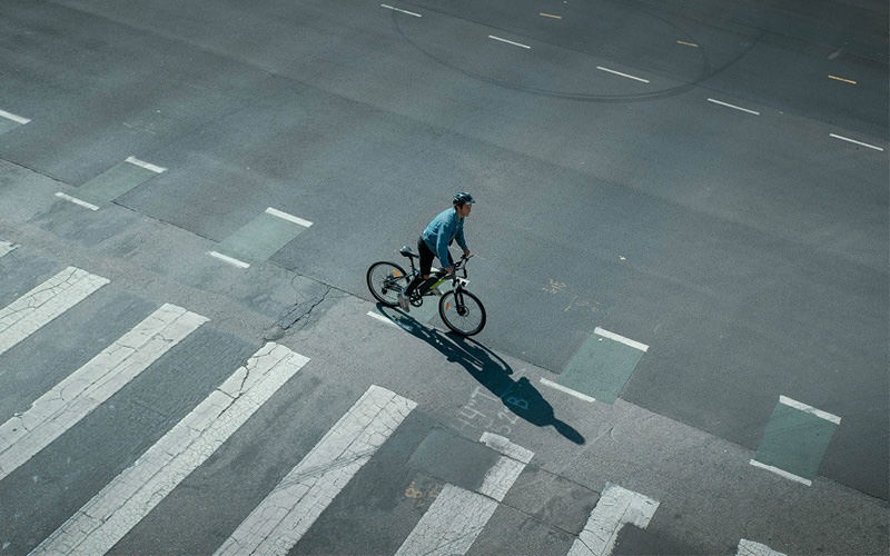 man riding a bicycle across street crosswalk